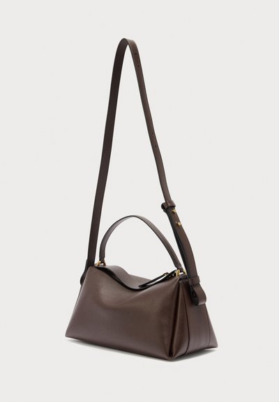 Καφέ σκούρο δερμάτινη τσάντα με λαβή στο πάνω μέρος και μακρύ ρυθμιζόμενο λουρί ώμου, εμφανίζεται σε απλό φωτεινό φόντο.