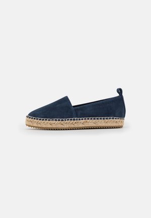 Espadrillo de ante azul marino con suela de yute trenzado y costuras en contraste. Incluye una tira en la parte trasera para facilitar su colocación. Diseño de punta redondeada.