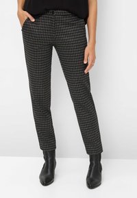 Zwart-grijs houndstooth patroon broek gemaakt van textuurstof, met een slim fit en zijzakken. Gepaard met zwarte enkellaarsjes.