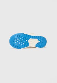 Shoe sole featuring a textured design in blue and cream, with a hexagonal pattern for grip and stability. Accented with raised edges.