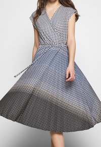 Blå och grå klänning med omslagdesign, korta ärmar och knytning i midjan. Har ett texturerat skalfmönster som övergår från blått till svart.