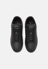 Czarne skórzane sneakersy z płaskim czarnym sznurkiem, okrągłym noskiem i logo na języku. Gładka faktura z subtelnymi detalami przeszyć.
