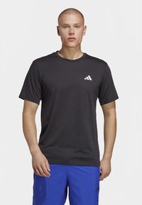 Sort atletik t-shirt lavet af letvægtsmateriale med korte ærmer og rund halsudskæring. Bemærkelsesværdigt hvidt Adidas-logo på venstre bryst.