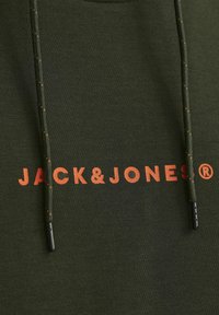 Grøn hættetrøje med "JACK & JONES" logo i orange, med kontrasterende snore, tekstureret stof og mørke plastikspidser på snørebåndet.