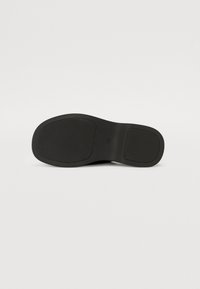 Black rubber shoe sole with a textured finish, featuring two distinct sections, curved edges, and no visible branding or patterns.