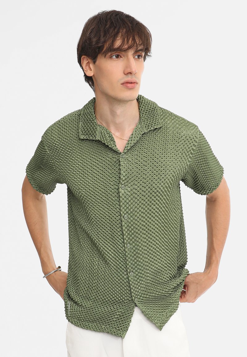 Groene korte mouw shirt gemaakt van textuurstof met een stippenpatroon, met een kraag en knopen aan de voorkant.