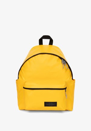 Żółty plecak o zaokrąglonym kształcie, wykonany z trwałego materiału. Posiada czarne akcenty, uchwyt na górze i przednią kieszeń na zamek.