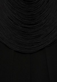 Černý textil s texturovaným, skladovaným designem nahoře, plynule přecházející do hladké, ploché části níže. Celkově monochromatický vzhled.