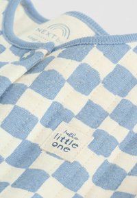 Body din bumbac cu model în carouri albastre și crem. Are o etichetă textilă cu inscripția „hello little one" și un nasture albastru.