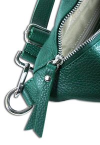 Groene leren handtas met een gestructureerde afwerking, voorzien van zilverkleurige metalen accenten, een ritsluiting en een afneembare band. De binnenvoering is licht van kleur.