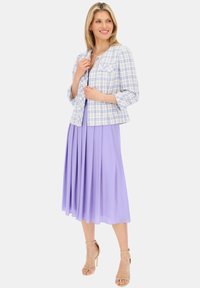 Jasnoniebieska i biała marynarka w kratkę z trzema czwartymi rękawami, zestawiona z plisowaną lawendową sukienką. Obie części mają długość do kolan.