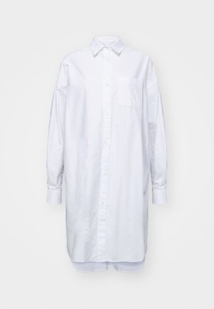 Chemise blanche longue à boutons, en coton, avec un col, des manches longues et une poche poitrine brodée.