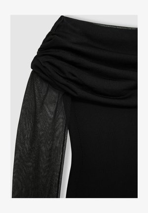 Zwarte jurk met een gedrapeerde, textuur overlay en een aansluitend lijfje. De stof is glad, met doorschijnende accenten op de mouwen.