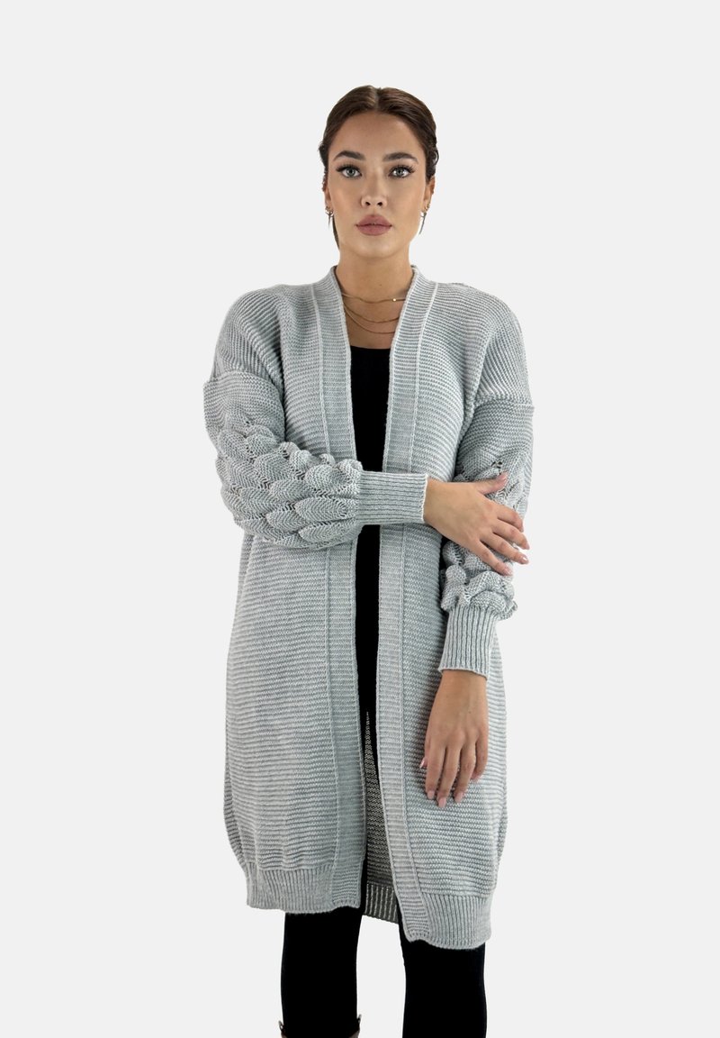 Hellgrauer Strickcardigan mit strukturierten Ärmeln, offenem Design und gerippten Bündchen. Der Stoff hat eine weiche, mittelschwere Textur.