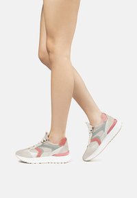 Scarpe da ginnastica grigie e rosa con una parte superiore in rete e camoscio, dotate di una suola bianca spessa e un elemento a contrasto sul tallone.