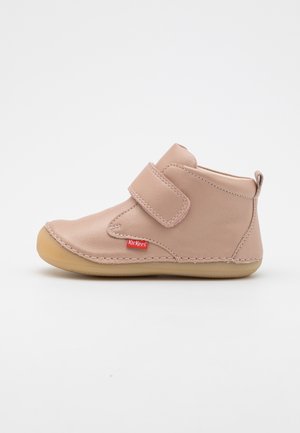 Light pink toddler shoe with rubber sole, stitched details, and a wide Velcro strap closure on a white background.