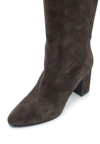 Stivale in suede marrone fino al polpaccio con punta affusolata e tacco a blocco su sfondo bianco.