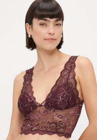 Burgundijska čipkana bralette s valovitom izrezom i cvjetnim uzorkom, s podesivim trakama i prozirnom, teksturiranom završnom obradom.