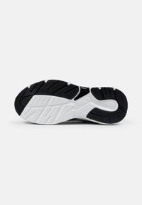 Sola di scarpa sportiva in bianco e nero con gomma testurizzata per la presa, un motivo di battistrada distintivo e il marchio "Fila" sulla parte centrale.