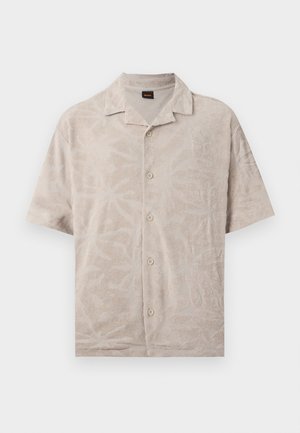 Camisa de manga corta color beige con botones, patrón sutil de hojas texturizadas y cuello pequeño, extendida sobre un fondo blanco.