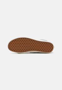 Sola de sneaker em borracha com textura hexagonal em castanho, contornada por borracha de cor creme. O design inclui uma borda lisa e um perfil plano.
