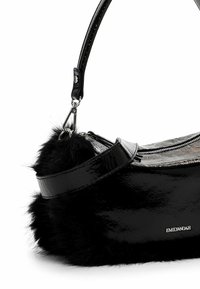 Black patent handbag with faux fur accents, a curved shape, and a sleek handle. Features a silver logo and shiny texture. Zipper closure visible.