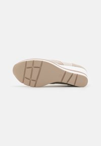 Beige athletic shoe sole with a textured rubber grip and diagonal lines, featuring a white midsole and subtle branding detail.