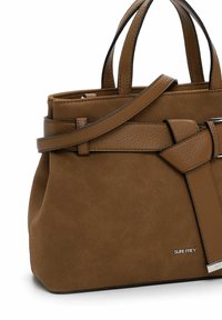 Bruine suède handtas met twee korte handvatten, een lange schouderband en een leren ceintuurdetail aan de voorkant, met een klein zilveren logo.