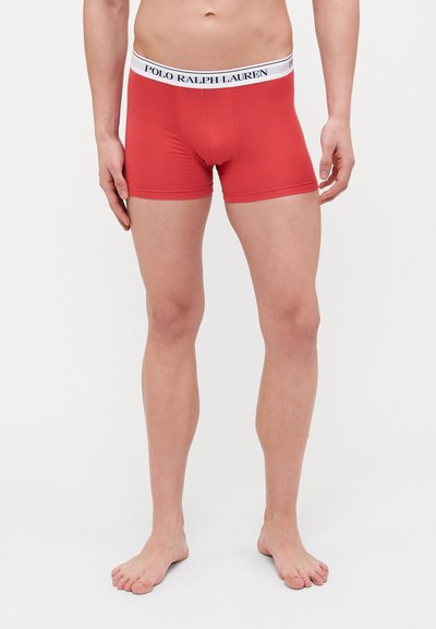 Boxers vermelhos feitos de um tecido elástico com uma cinta branca onde está impresso "POLO RALPH LAUREN" em preto. Design ajustado.