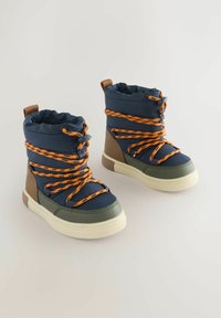 Marinblå isolerade kängor med orange snören, gröna detaljer och en slitstark yta. Med en vadderad krage och kontrasterande sula.