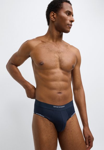 Vīriešu apakšbikses tumši zilā krāsā ar elastīgu jostasvietu, kurā izšūts balts «Emporio Armani» zīmols. Gluda auduma tekstūra un pieguļošs dizains.