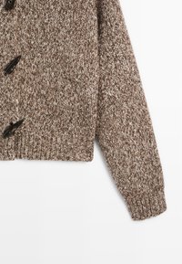 Hnědý pletený kardigan s texturovaným vzorem, velkými černými knoflíky a žebrovanými manžetami. Měkký, silný materiál, zkrácený design.