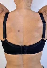 Sujeción negra con tirantes ajustables, tela suave y cierre de gancho. Presenta un diseño sencillo sin decoraciones visibles.