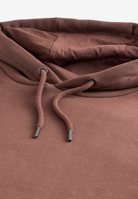 Sudadera con capucha marrón de textura suave, que incluye un cordón con puntas de metal y un interior forrado y acogedor.