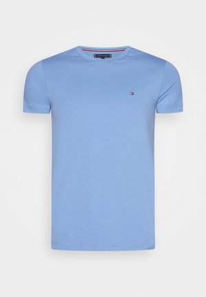 Camiseta de manga corta de cuello redondo en azul claro, con un pequeño logo de Tommy Hilfiger en el lado izquierdo del pecho y detalles de marca en el cuello.