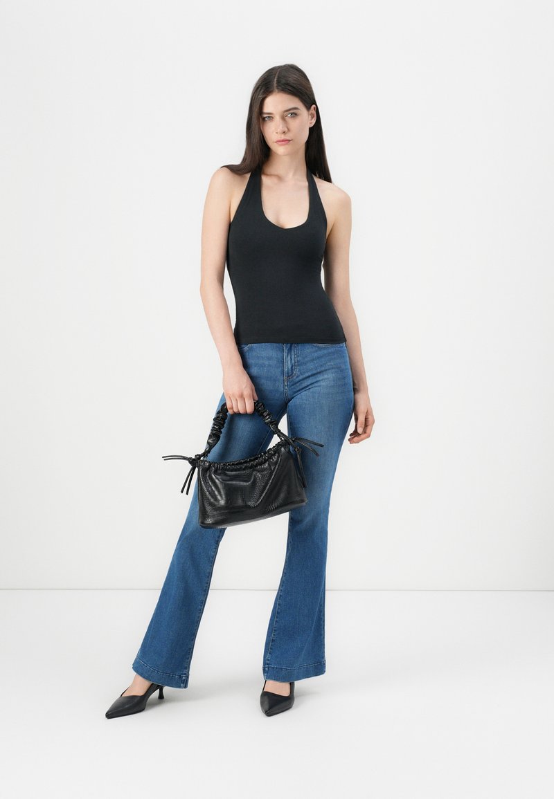 Haut dos nu noir, jean évasé bleu, escarpins pointus noirs et un sac à main texturé noir avec des poignées froncées et des nœuds.