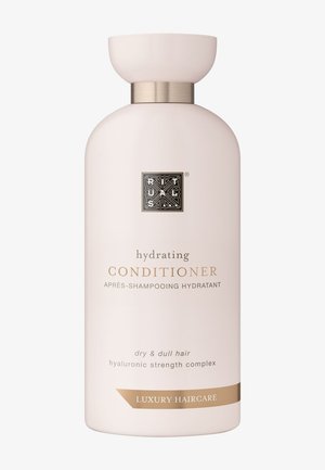 Après-shampooing hydratant dans une bouteille rose pâle avec un accent doré métallique. Présente un logo et des étiquettes en relief à l'avant, destiné aux cheveux secs et ternes.