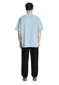 Jasnoniebieska, oversize koszulka z krótkim rękawem, wykonana z bawełny, w połączeniu z czarnymi dresami. Strój charakteryzuje się luźnym krojem.