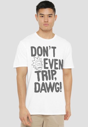 Young man wearing a white T-shirt with cartoon face and large text reading "DON'T EVEN TRIP, DAWG!" standing against a plain background.