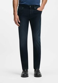 Mörkblå denimjeans med smal passform, som har fem fickor och dragkedja. Slät yta med en lätt glans. Förstärkta sömmar.