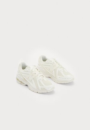 Pair of white athletic sneakers with mesh and synthetic overlays, lace-up design, and cushioned soles placed on a plain light background.