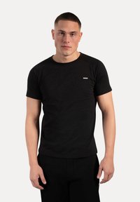 Czarny t-shirt z krótkim rękawem wykonany z miękkiego materiału, z okrągłym dekoltem i małym logo na klatce piersiowej.