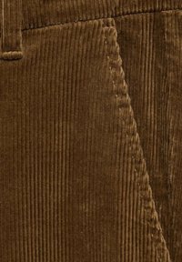 Tissu en velours côtelé marron avec nervures verticales, texture douce et léger éclat. Coutures visibles en accent et bords nets découpés.