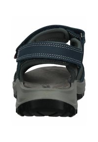 Námořnické sandály vyrobené z syntetického materiálu, s nastavitelnými suchými zipy, polstrovanou stélkou a texturovanou černou gumovou podrážkou.