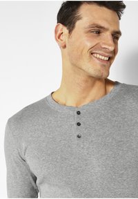 Graues Langarm-Henley-Shirt mit Rundhalsausschnitt, drei Knöpfen vorne und einem weichen, strukturierten Stoff.