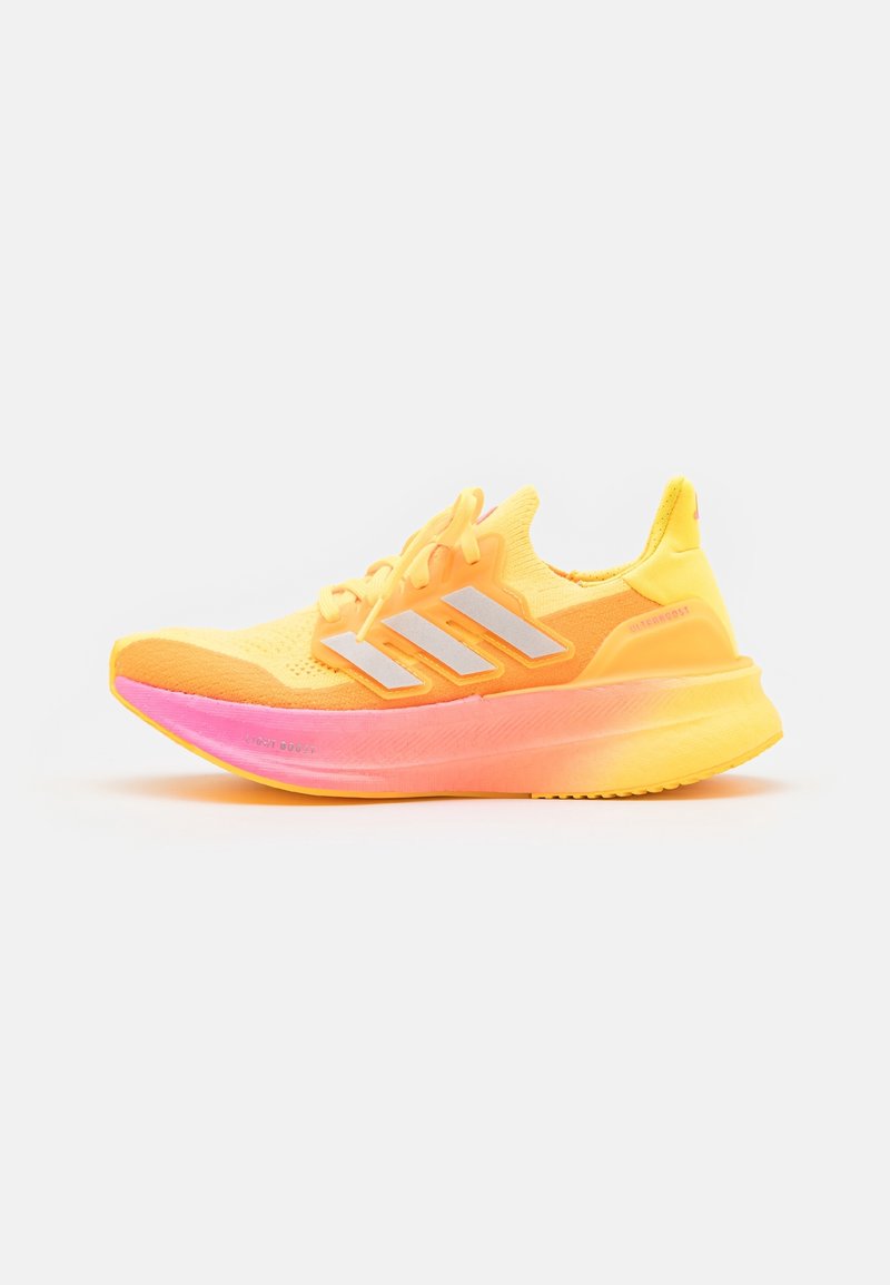Chaussure de course jaune vif et rose avec logo blanc à trois bandes et semelle amortissante, présentée de profil sur fond blanc.
