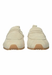 Pari beigeä mokkanahkaista slip-on -loaferia, joissa on vaaleanruskeat kumipohjat, katsottuna edestä pyöristettyjen kärkien ja vähäisten ompelu yksityiskohtien kanssa.