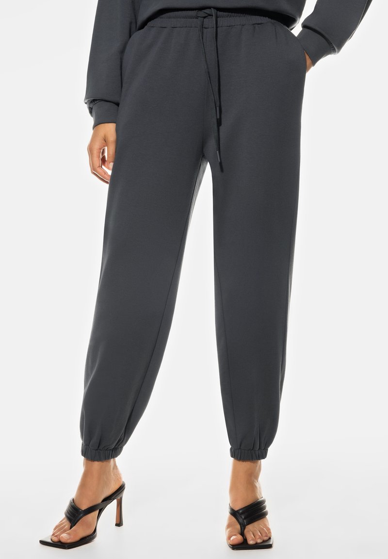 Donkergrijze sweatpants van zachte stof, met een elastische tailleband met een koord, taps toelopende boorden en zijzakken.