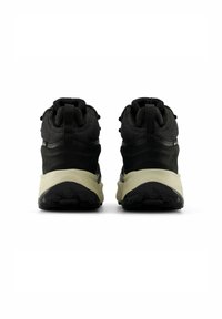 Zapatillas altas negras con una parte superior texturizada, cuello acolchado y una entresuela de color beige claro en contraste con la suela de goma negra.