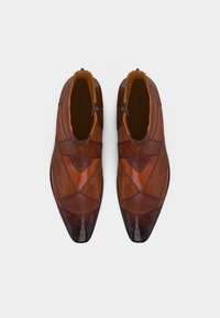 Καφέ δερμάτινα μποτάκια αστραγάλου με πατσγουορκ υφασμάτων και πλαϊνό φερμουάρ, σε άποψη από πάνω σε λευκό φόντο.